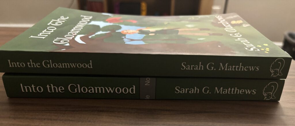 Book cover spines for Into the Gloamwood. The top one from Draft2Digital has smaller title text and a different style.
